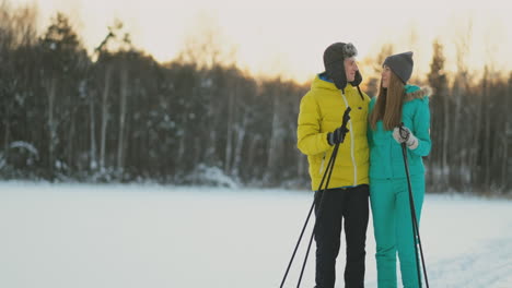 A-man-in-a-yellow-jacket-and-a-girl-in-a-blue-jumpsuit-skiing-in-slow-motion-at-sunset